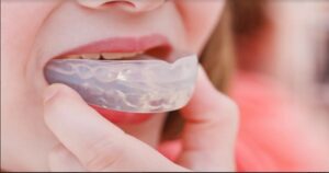 A picture of a woman putting on her mouthguard