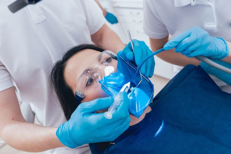 A picture of a patient and two dentists in the middle of a dental procedure